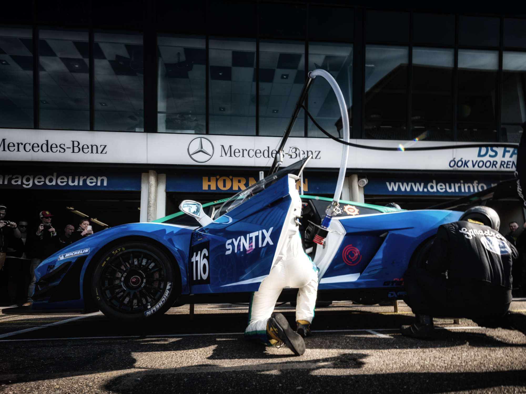 Syntix-branded race car in a pitstop at a professional race track, logo visible on vehicle