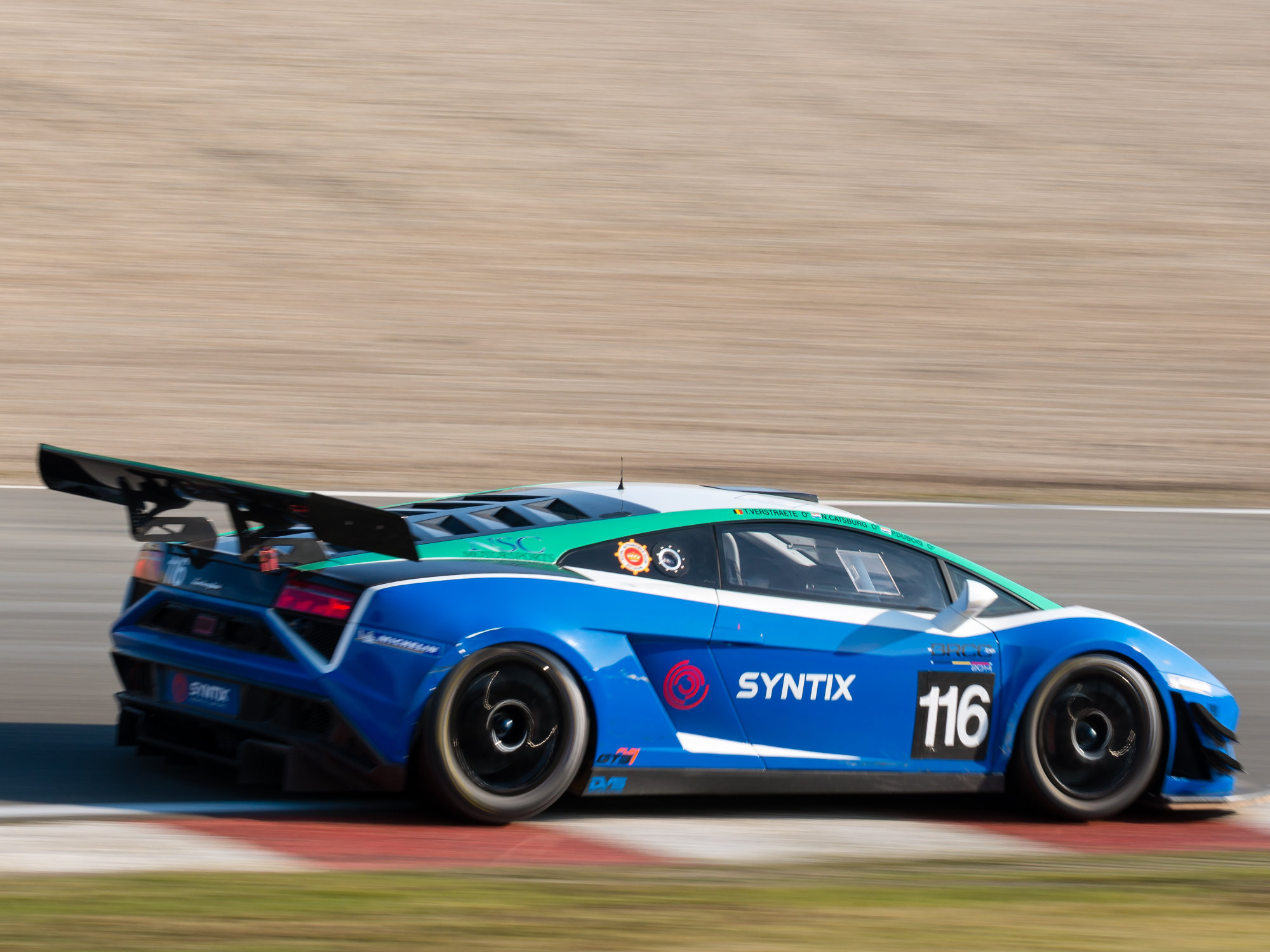 Syntix-liveried race car featuring red and blue graphics and logo, parked in a motorsport setting