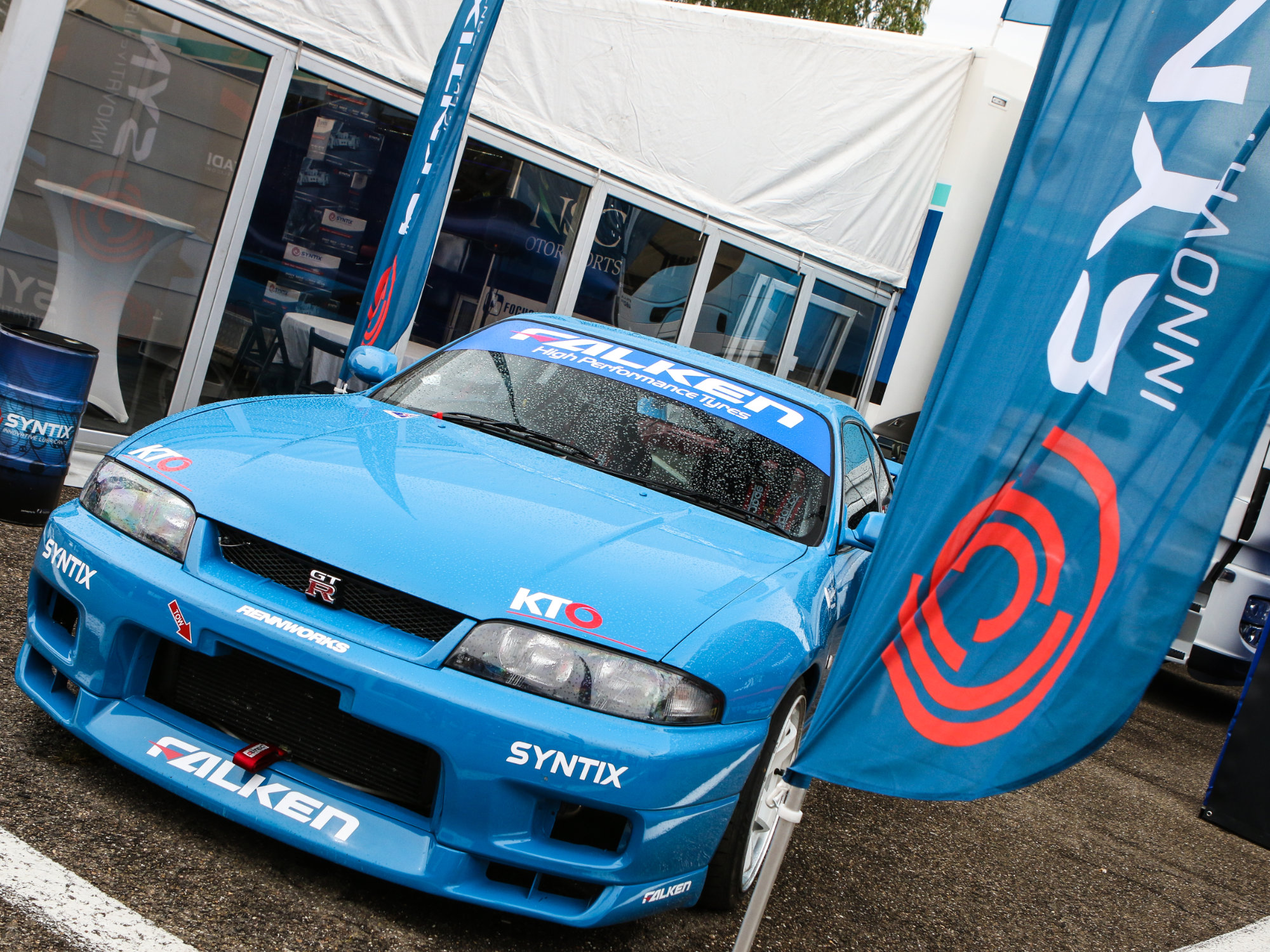 Syntix flags flying beside a race car, combining dynamic branding with motorsport energy