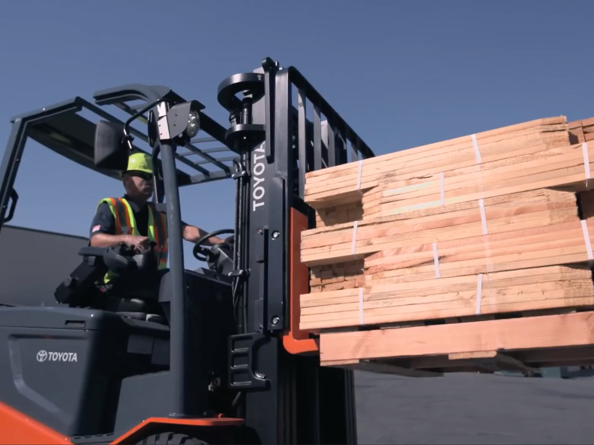 Toyota forklift operator moving stacked lumber on an outdoor construction site
